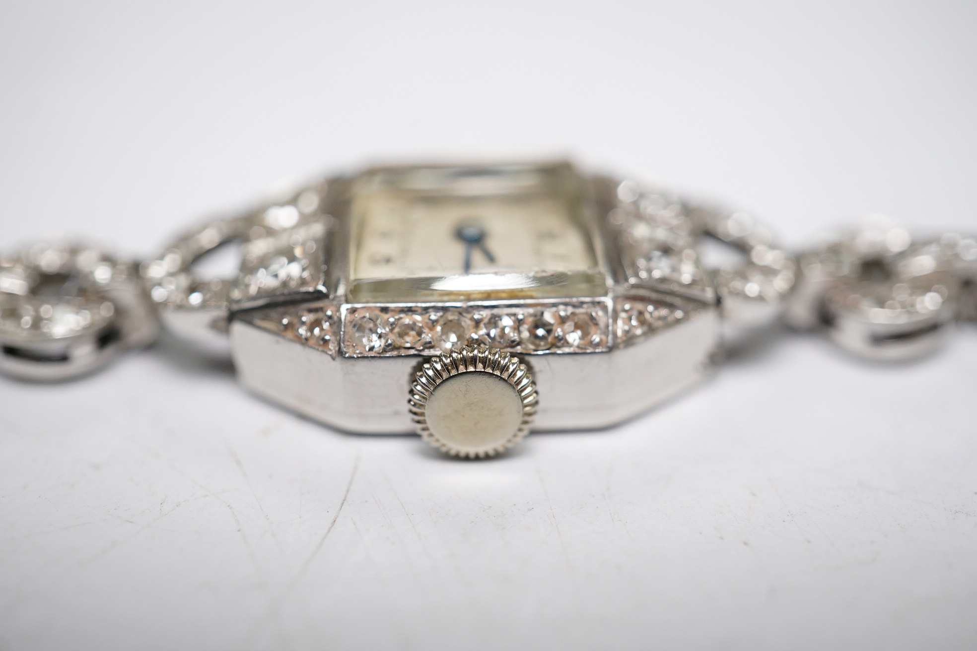 A lady's 1950's white metal and diamond cluster set manual wind cocktail watch, on a 9ct white gold bracelet, overall length 17.5cm, gross weight 17.1 grams. Condition - fair